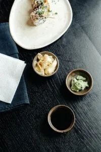 Top view of a delicious sushi dish with soy sauce, wasabi, and ginger on a dark wooden table.